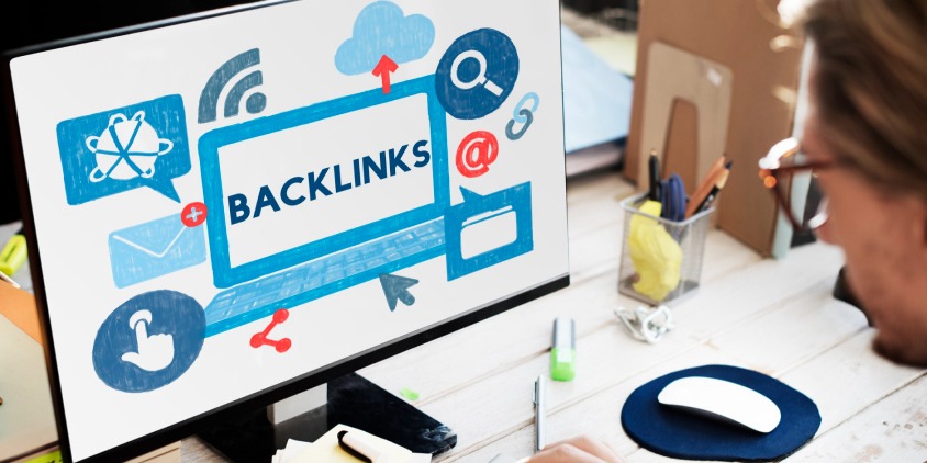 A person working on a computer displaying a graphic about backlinks and link-building strategies for SEO improvement.