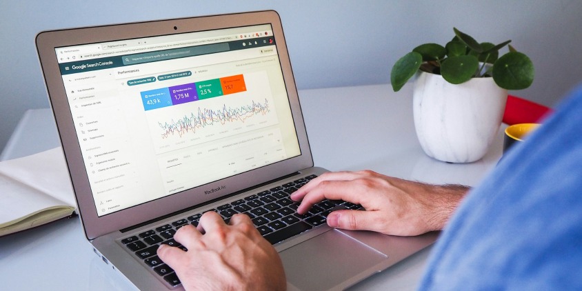 Hands typing on a laptop displaying Google Search Console performance data, representing technical SEO optimization for website ranking improvement.